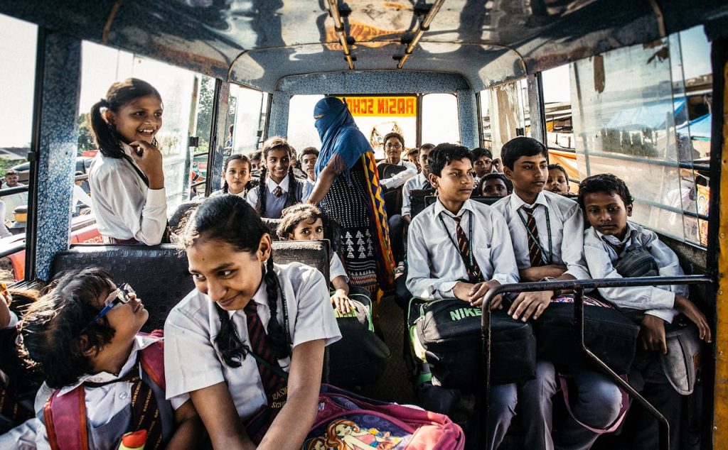 The Art of Drawing Readers In: Your attractive post title goes here Group of school children in uniforms on a bus in Wadgaon, India.